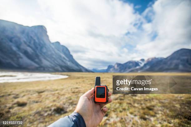 adventurer holds mini gps and satellite safety communication device. - global positioning system stock pictures, royalty-free photos & images