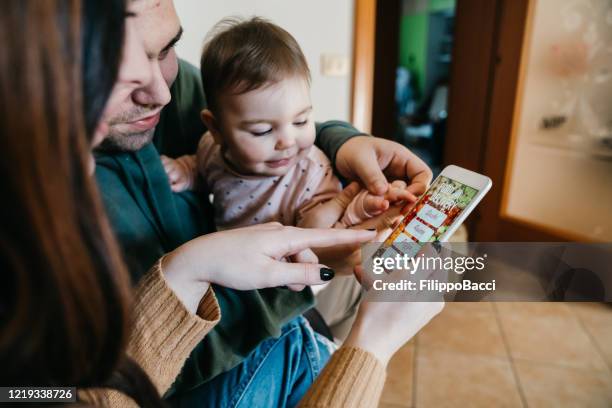 familie auf dem sofa zu hause - mama bestellt etwas lieferessen zum abendessen - ordering stock-fotos und bilder