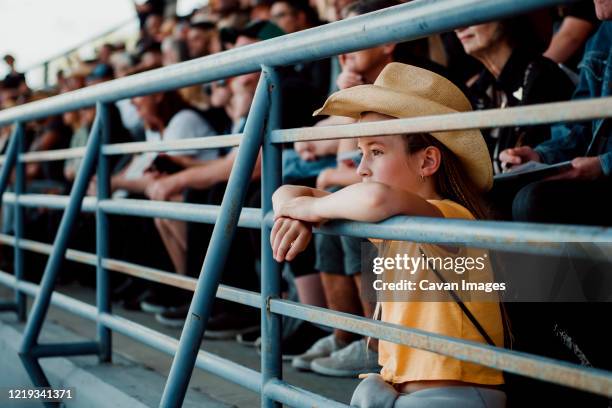 little girl watching the rodeo with a cowboy hat on - rodeo stock-fotos und bilder