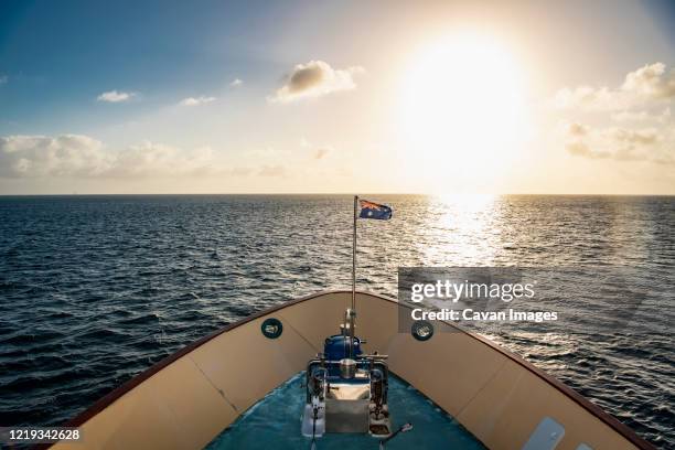 australian exploration vessel heading into the setting sun - proas fotografías e imágenes de stock