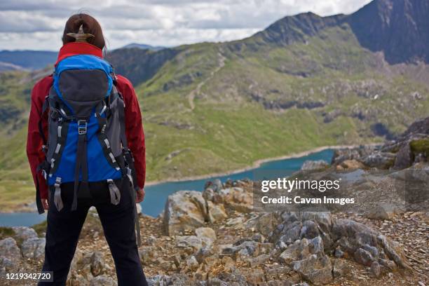 woman with rucksack overlooking a mountain lake on snowdonia - llanberis stock pictures, royalty-free photos & images