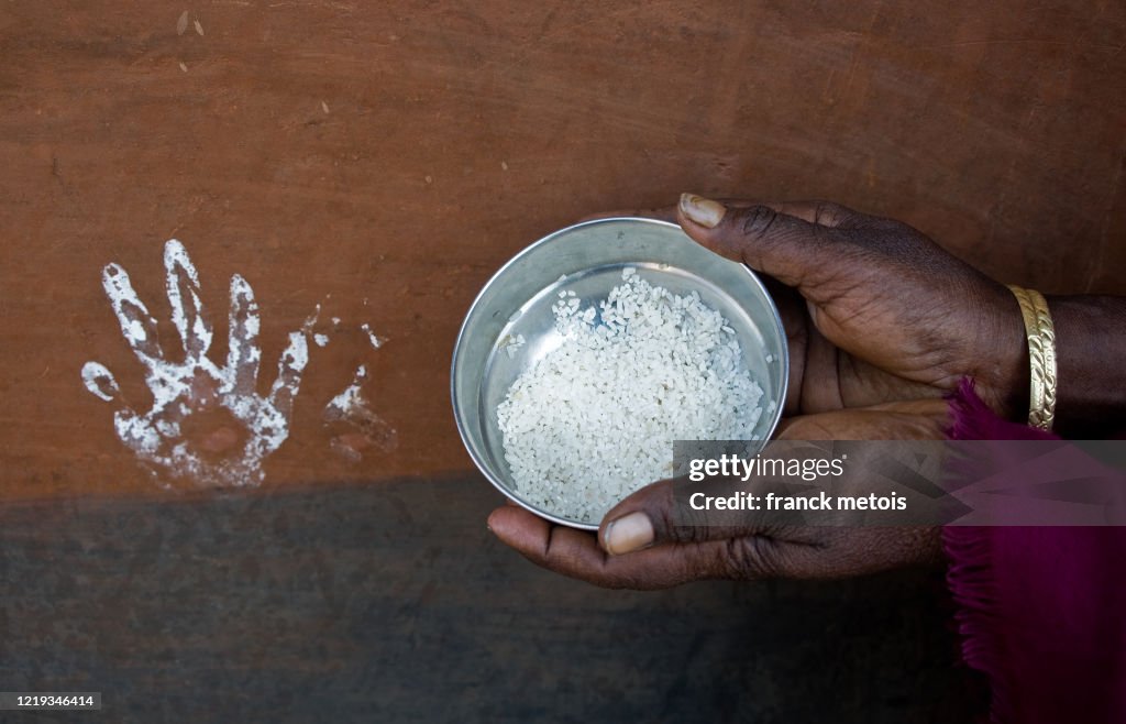 White handprint on a mud wall + tribal woman holding a bowl of rice ( India)
