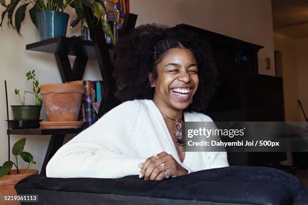 portrait of laughing african-american woman at home - showus hair stock pictures, royalty-free photos & images