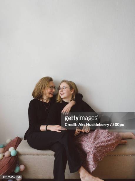 Smiling mother and daughter sitting together and embracing
