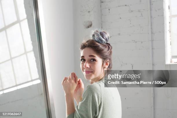 indoor portrait of smiling mid adult woman looking at camera - hair bun stockfoto's en -beelden