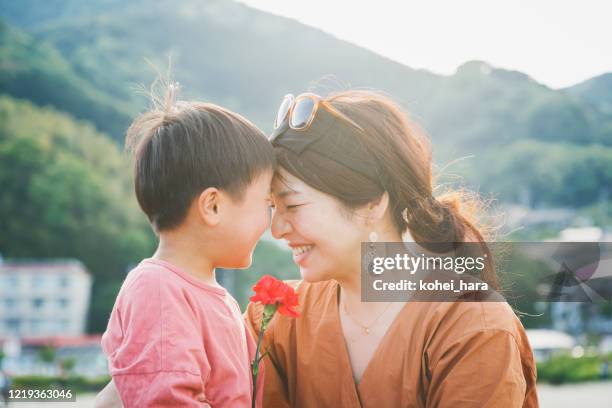 ragazzo che consegna alla madre un fiore di garofano - child giving gift foto e immagini stock