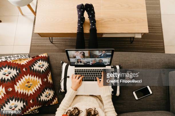 junge frau mit einem laptop, um mit ihren freunden und verwandten während der quarantäne zu verbinden - millennial generation stock-fotos und bilder