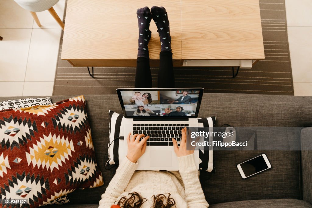 Jonge vrouw die laptop gebruikt om met haar vrienden en verwanten tijdens quarantaine te verbinden