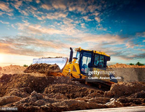 gele bulldozer bij een bouwwerf - construction equipment stockfoto's en -beelden