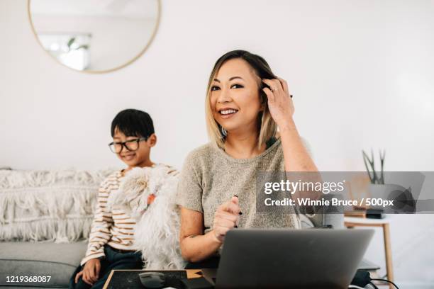 young working mother using laptop in living room - showus makeup stock pictures, royalty-free photos & images