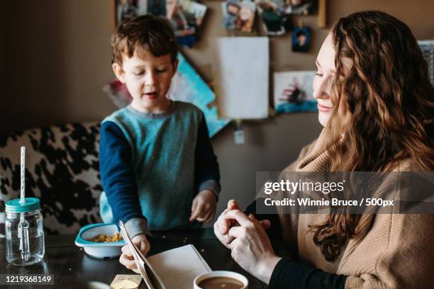 son showing mother his notebook during breakfast - single mother stock pictures, royalty-free photos & images