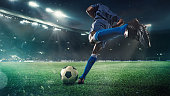 Football or soccer player in action on stadium with flashlights, kicking ball for winning goal, wide angle. Action, competition in motion