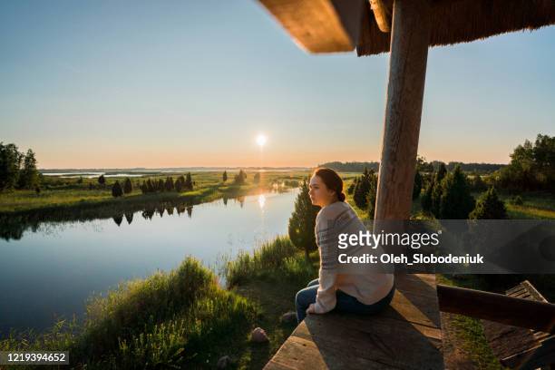 woman sitting on wooden fence  on swamp in estonia - latvia forest stock pictures, royalty-free photos & images