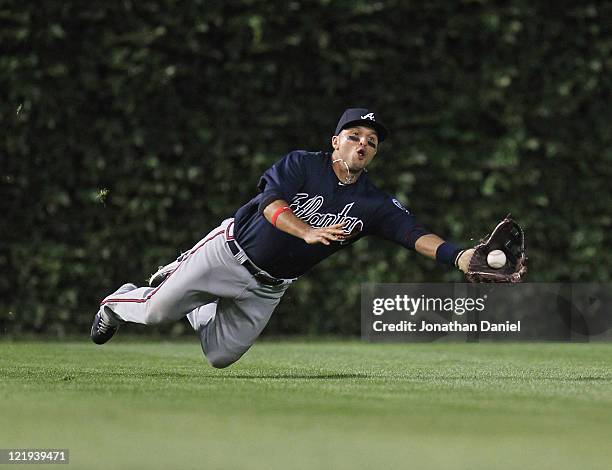 Martin Prado of the Atlanta Braves dives to make a catch on a ball hit by Alfonso Soriano of the Chicago Cubs at Wrigley Field on August 23, 2011 in...