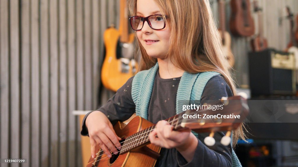 Dad teaching guitar and ukulele to his daughter.Little girl learning guitar at home.Close up.Ukulele class at home. Child learning guitar from her father