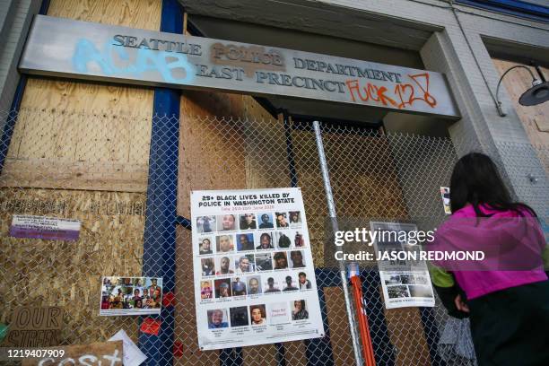 Graffiti and photos of people killed by police are pictured on a fence outside the closed Seattle Police Department's East Precinct now surrounded by...