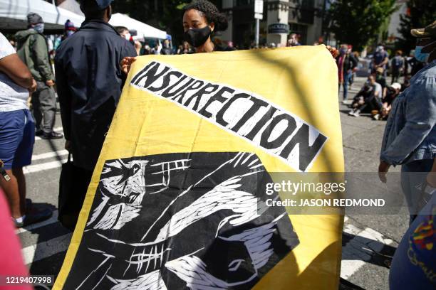 Sarah Tornai holds an "insurrection" flag that Human Rights Attorney Mike Withey saved from the WTO Seattle protests as people gather in the newly...