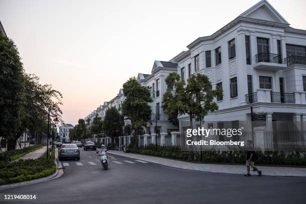 Motorcyclist travels along a road past a row of houses at the Vinhome Riverside complex, operated by Vingroup JSC, in Hanoi, Vietnam, on Wednesday,...