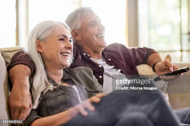 happy couple watching tv at home - woman finding grey hair stock pictures, royalty-free photos & images