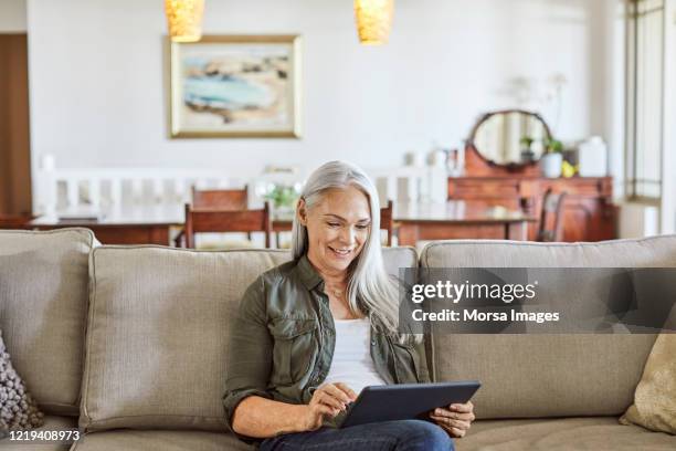 woman using digital tablet at home - finding gray hair stock pictures, royalty-free photos & images