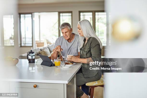 paar schaut nachrichten auf tablet-pc während des frühstücks - couple tablet house stock-fotos und bilder