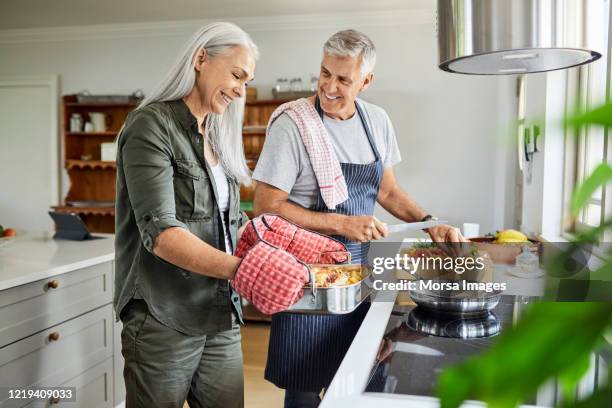 自宅で一緒に食べ物を準備するカップル - middle aged couple cooking ストックフォトと画像