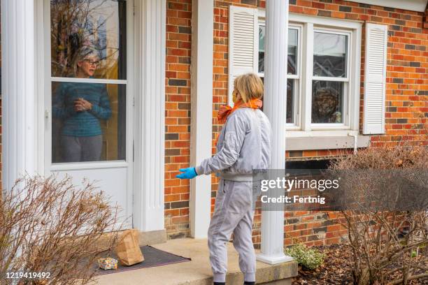 neighbors helping each other.  a friend drops off a bag of groceries and a small gift. - neighbours talking stock pictures, royalty-free photos & images