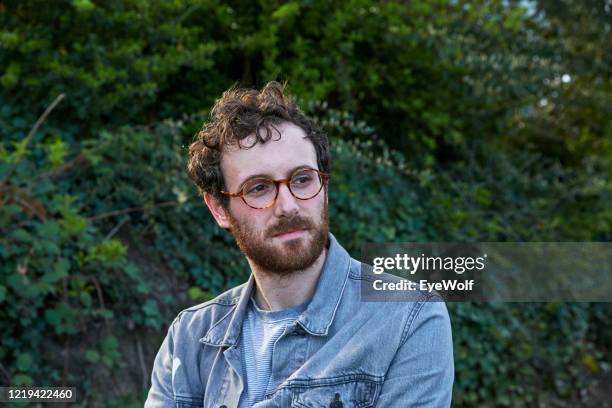 portrait of a man looking off camera against a background of green plants. - teal portrait stock pictures, royalty-free photos & images