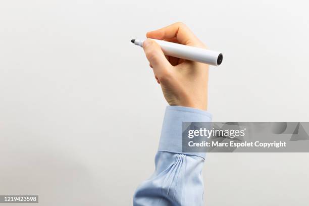 rised arm writing with a black marker in a transparent white board - blauw shirt stockfoto's en -beelden