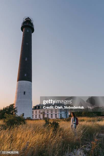 woman walking near the lighthouse on the beach at sunset - estonia stock pictures, royalty-free photos & images
