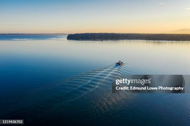 small ferry boat in route to the mainland during a beautiful sunrise. - kielwasser stock-fotos und bilder