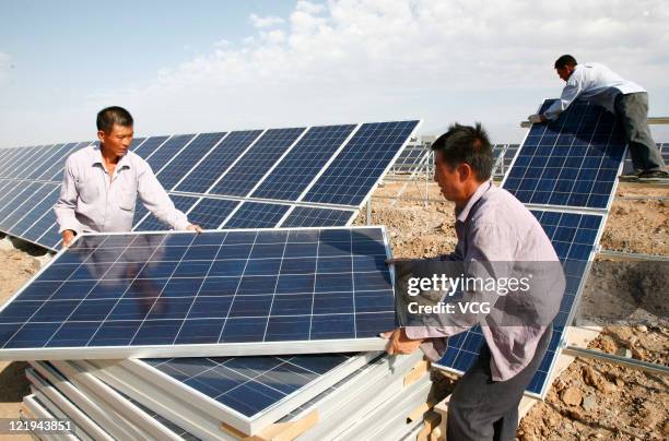 Construction workers install solar panels at Hami Solar Power Station on August 22, 2011 in Hami, Xinjiang Uyghur Autonomous Region of China. The...