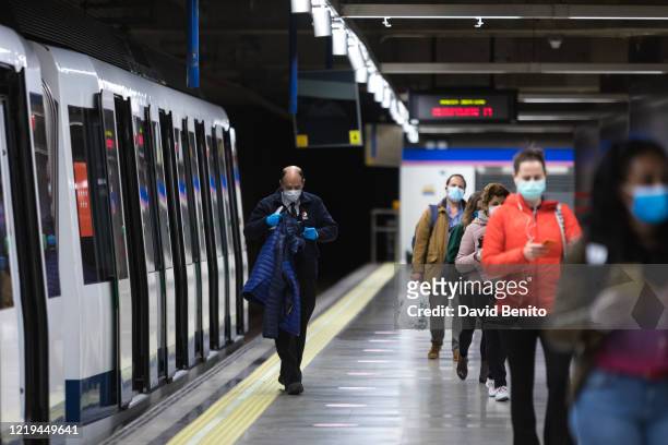 Passengers wearing face masks are seen at the Feria de Madrid metro station on April 17, 2020 in Madrid, Spain. Spain is beginning to reduce strict...