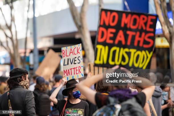 Protester hold a 'Black Lives Matter' and 'No more deaths in custody' placards during a demonstration. Australians hit the streets to demand direct...