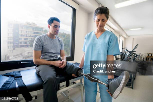 joven discapacitado usando una prótesis y haciendo fisioterapia - equipo protésico fotografías e imágenes de stock