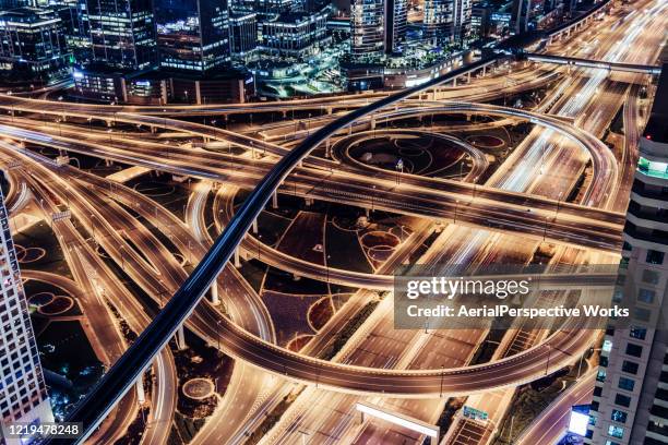 aerial view of overpass, metro and city traffic at night - dubai road stock pictures, royalty-free photos & images