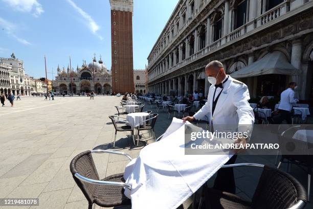 Waiter sets a table on June 12, 2020 at the terrace of the 18th Century Cafe Florian on St. Mark's Square in Venice, which reopens after being closed...