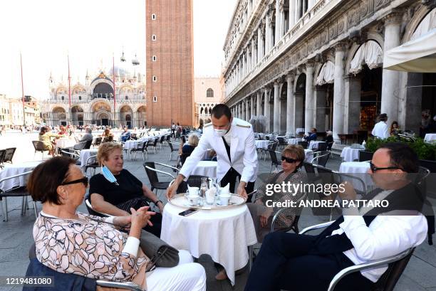 Waiter serves customers on June 12, 2020 at the terrace of the 18th Century Cafe Florian on St. Mark's Square in Venice, which reopens after being...