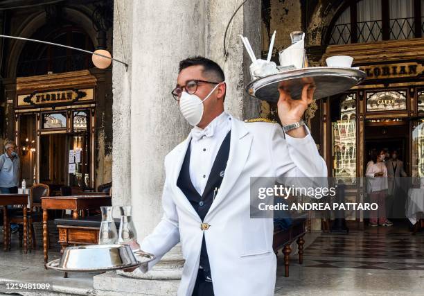 Waiter serves customers on June 12, 2020 at the terrace of the 18th Century Cafe Florian on St. Mark's Square in Venice, which reopens after being...