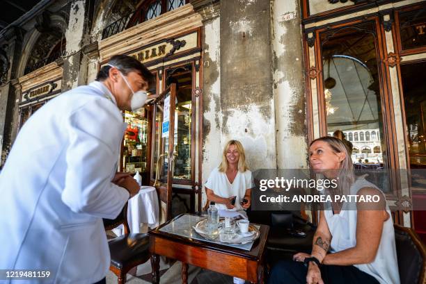 Waiter talks with customers on June 12, 2020 at the 18th Century Cafe Florian on St. Mark's Square in Venice, which reopens after being closed for...