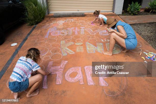 mother and two little daughters drawing with chalks on driveway - family chalk drawing stock pictures, royalty-free photos & images