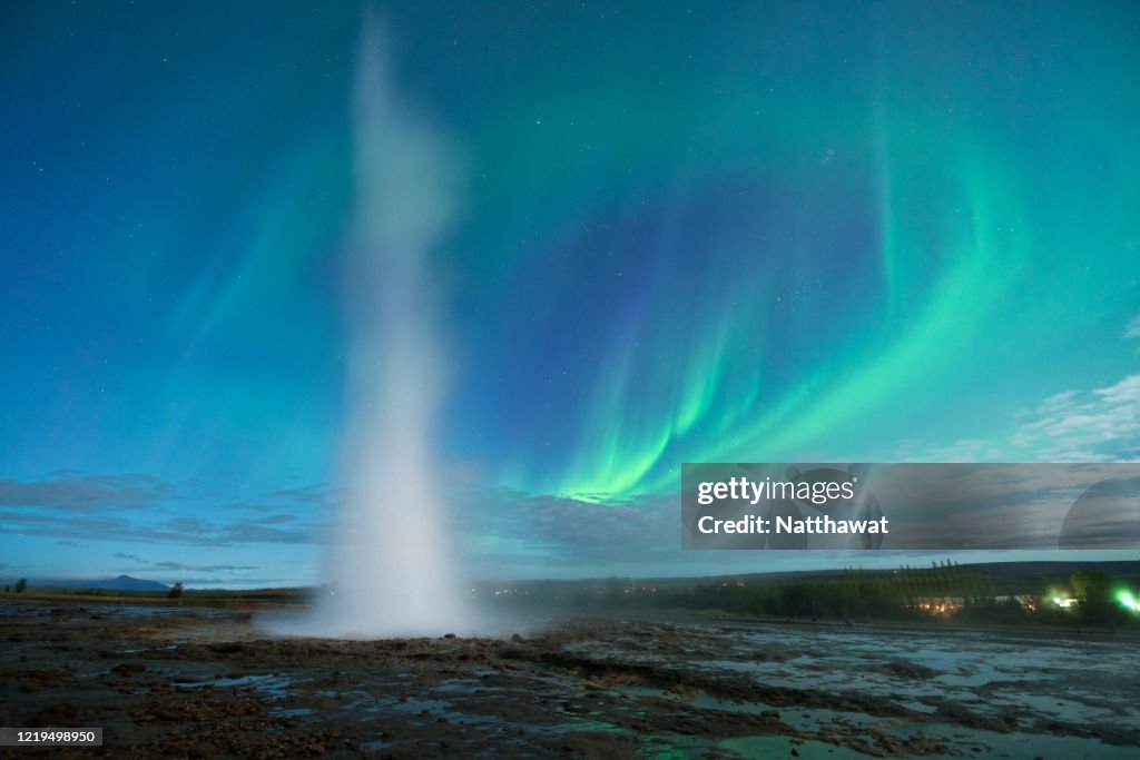 Aurora borealis curving over Strokkur Geysir in Iceland