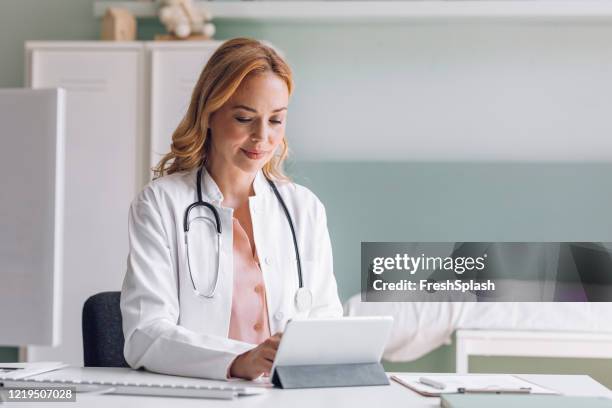 blonde medical doctor using a digital tablet at the office - referral stock pictures, royalty-free photos & images