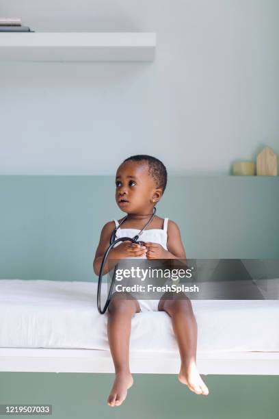 adorable african american baby girl playing with a stethoscope at the doctor's office - doctor and baby stock pictures, royalty-free photos & images