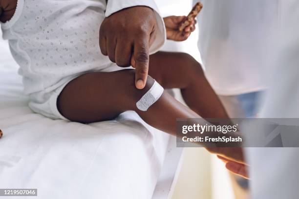 arts die op een verwonding van de knie van haar kleine patiënt richt - baby pointing stockfoto's en -beelden