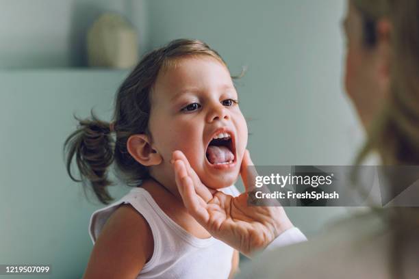 bambino a un controllo medico: pediatra che esamina la gola di una bambina - mal di gola foto e immagini stock