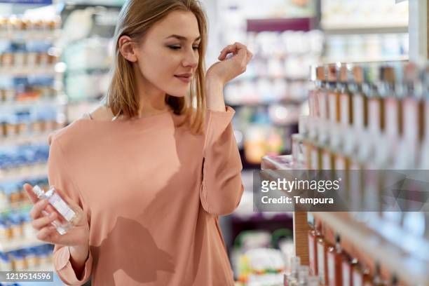 weibliche kundin kauft parfüm in einem geschäft - parfum stock-fotos und bilder