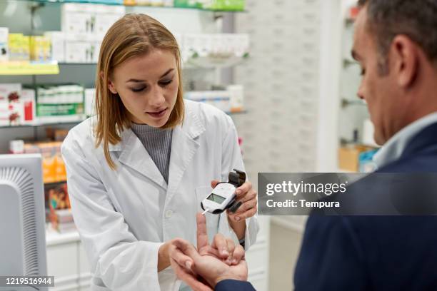 una enfermera está haciendo una prueba de azúcar para la diabetes a un paciente. - glycemia fotografías e imágenes de stock