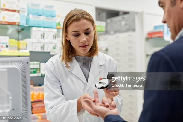 una joven farmacéutica haciendo una prueba de azúcar para la diabetes a un paciente. - glycemia fotografías e imágenes de stock