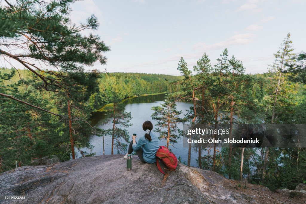 Mujer mirando al lago en Finlandia y bebiendo té